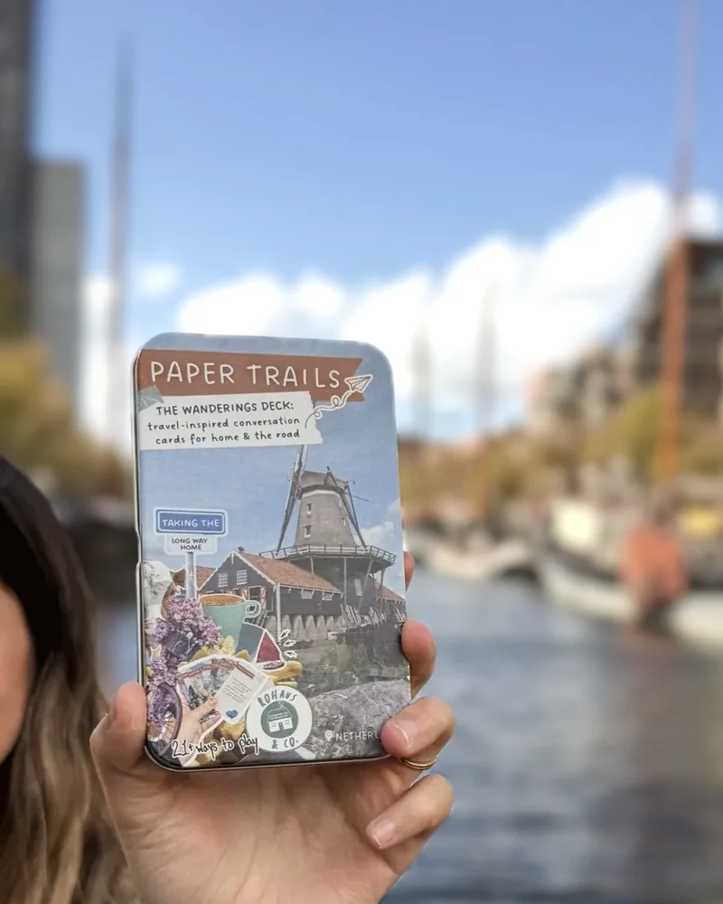 A Paper Trails tin held up by a canal